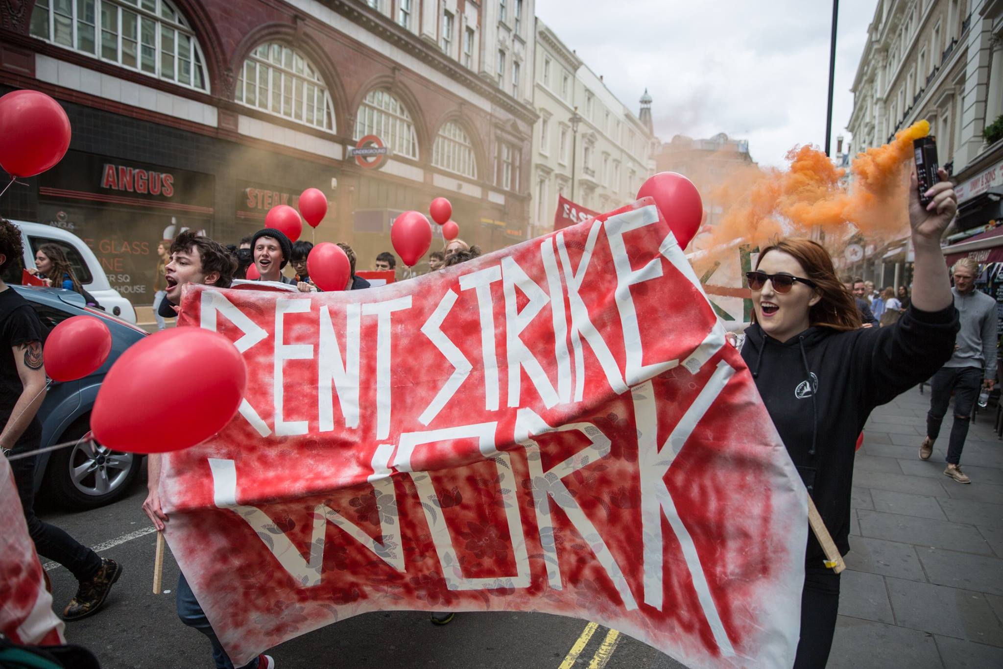 Group of students on the street in London with a banner that reads "Rent Strikes Work"